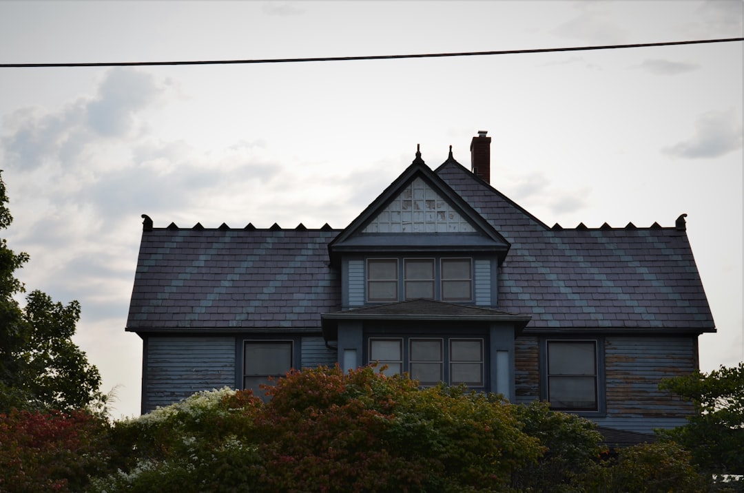 A clean, architectural detail shot of a newly installed roof, focusing on the perfectly aligned shingles and the crisp metal drip edge against a clear sky.