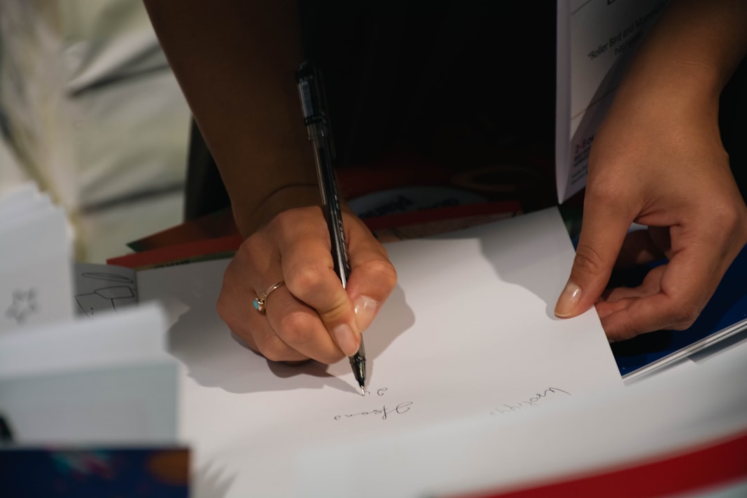 A person sits at a bright, well-lit table carefully signing real estate documents, representing the financial decisions involved in a home sale.