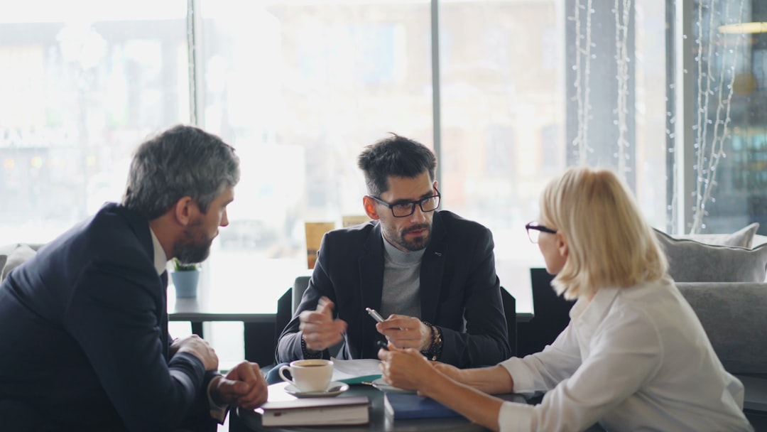 A serious couple sits at a bright, modern table reviewing a report with their real estate agent, representing the critical negotiation phase after a home inspection.