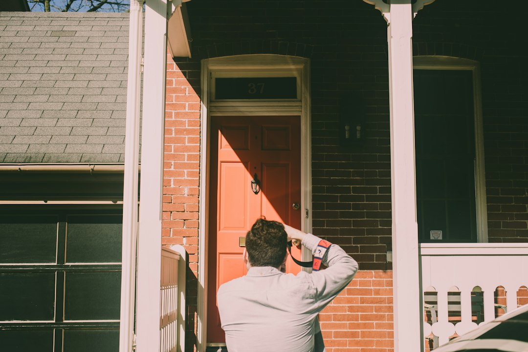 Close-up of a hand holding a set of house keys, with the blurred background of a residential home, representing a successful real estate transaction.