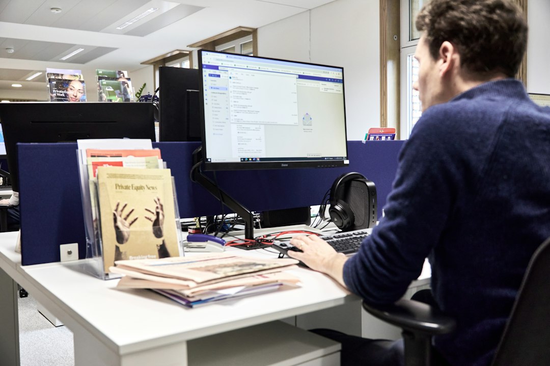 Person sits at a clean, organized desk carefully reviewing financial documents and using a calculator, symbolizing the imp...